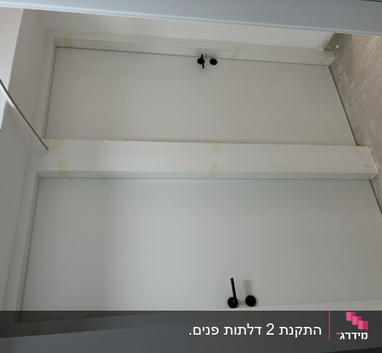 שתי דלתות לבנות עם ידיות שחורות